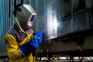 Steel worker working on a steel beam wearing full safety gear. 